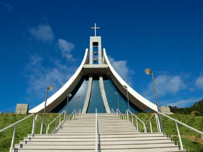 Imponente Santuário de Santa Paulina em Nova Trento - SC com sua arquitetura moderna e uma cruz iluminada sob um céu azul.